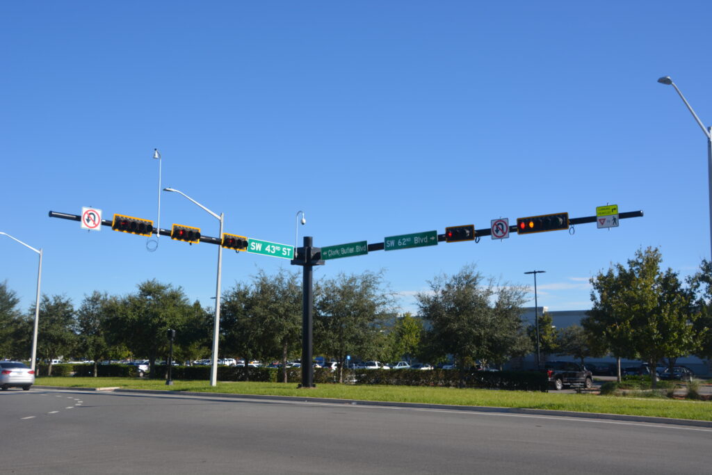 Traffic signal on the corner of sw 43rd st and sw 62nd blvd. trees can be seen in the background and the sky is clear and blue.